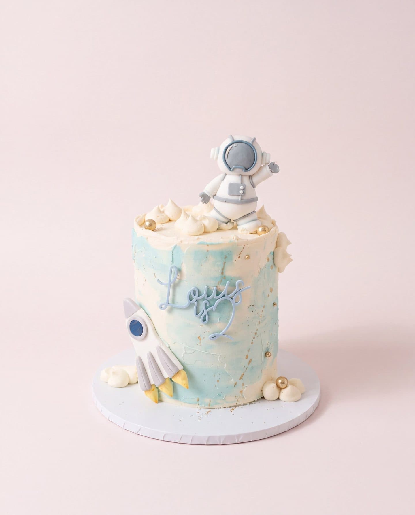 Pale blue birthday cake with an astronaut and a rocket