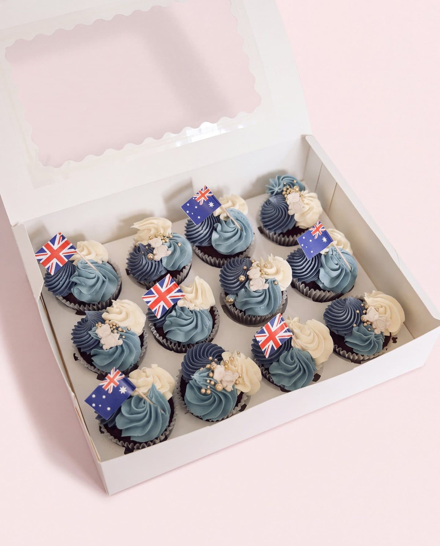 A box of blue and white cupcakes with Union Jack and Australian flags