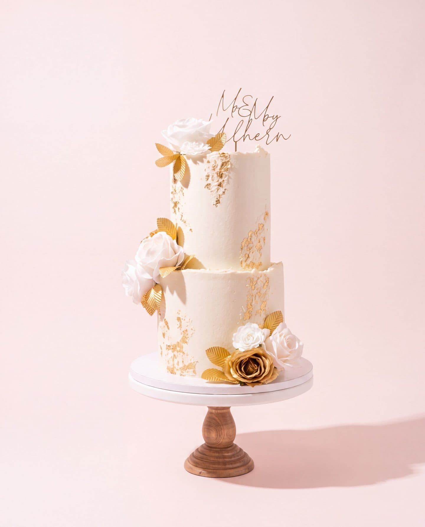 Two tier white wedding cake with gold leaf and sugar roses