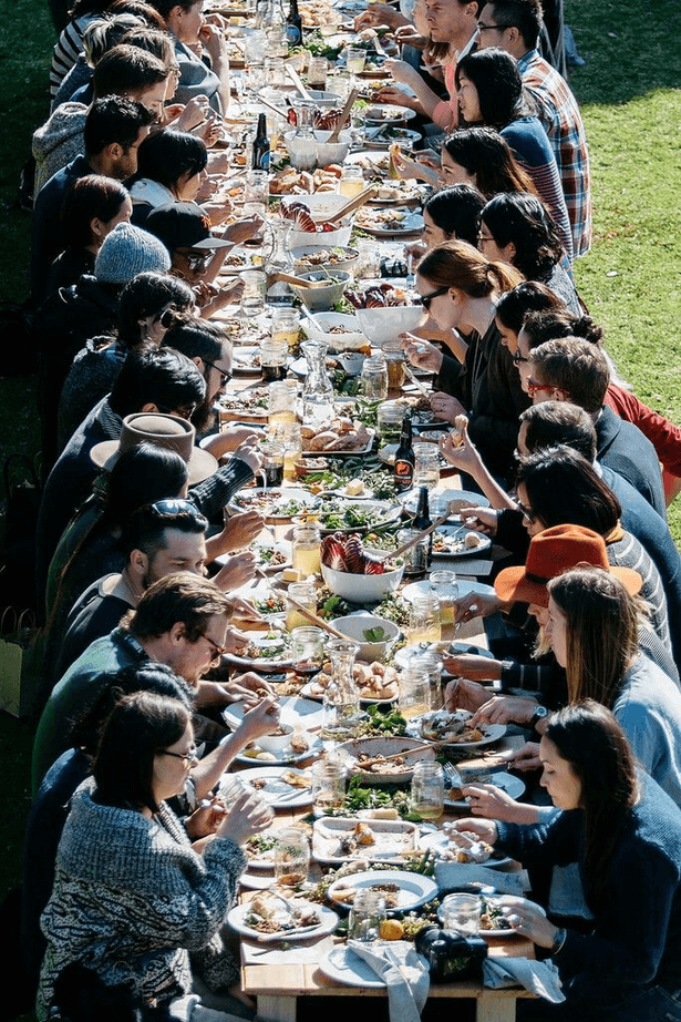 Long shared dinner table, candlelight, plates, conversation