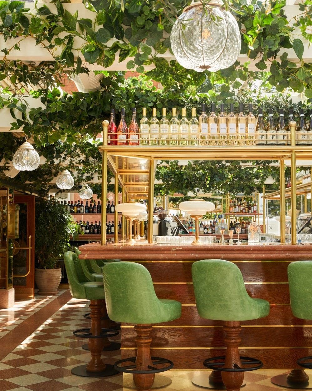 Interior of an Alderley Edge restaurant with a brass bar and trailing greenery.