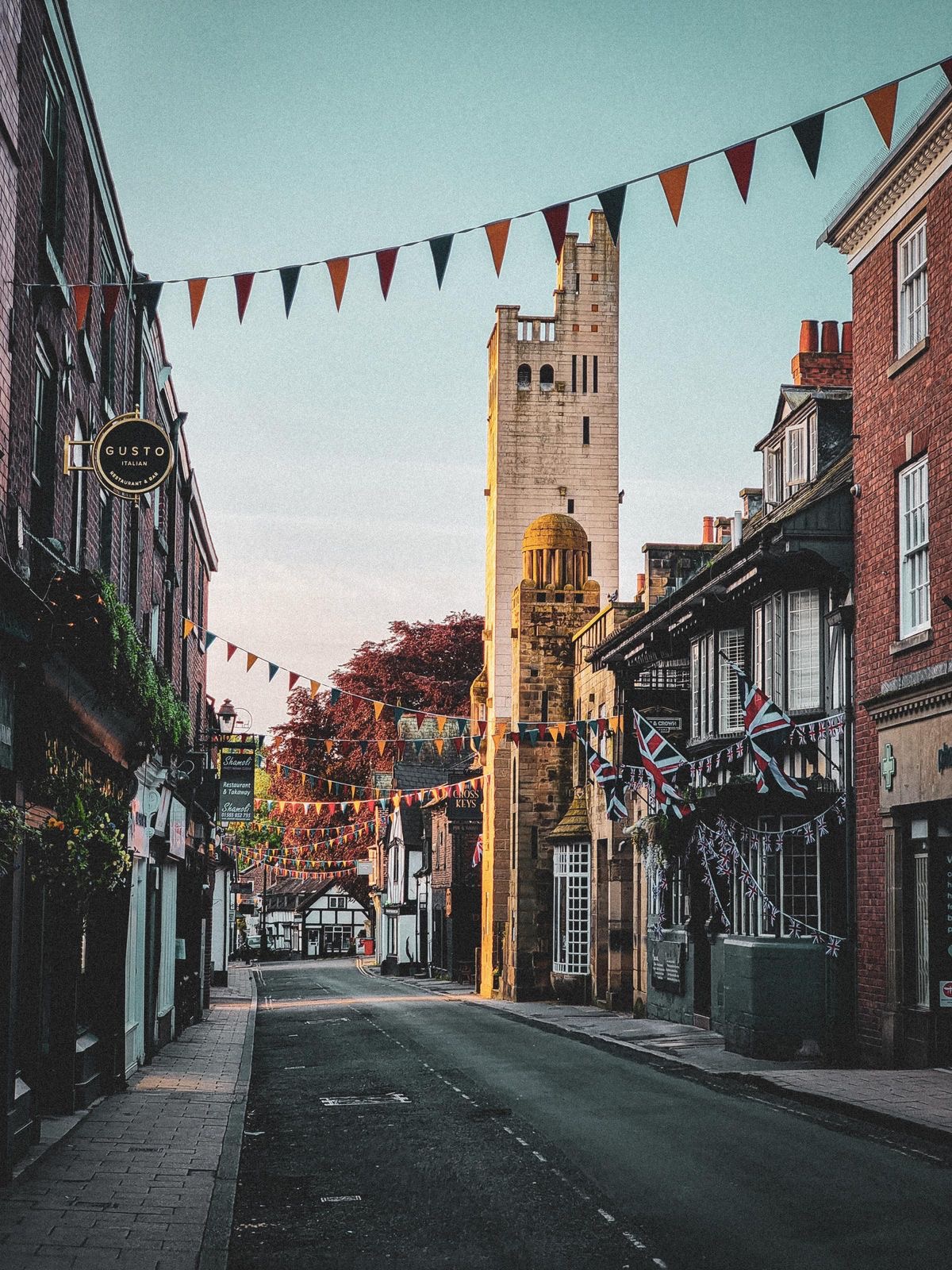 King Street in Knutsford at golden hour, bunting strung between the buildings and the tower at the end of the street.