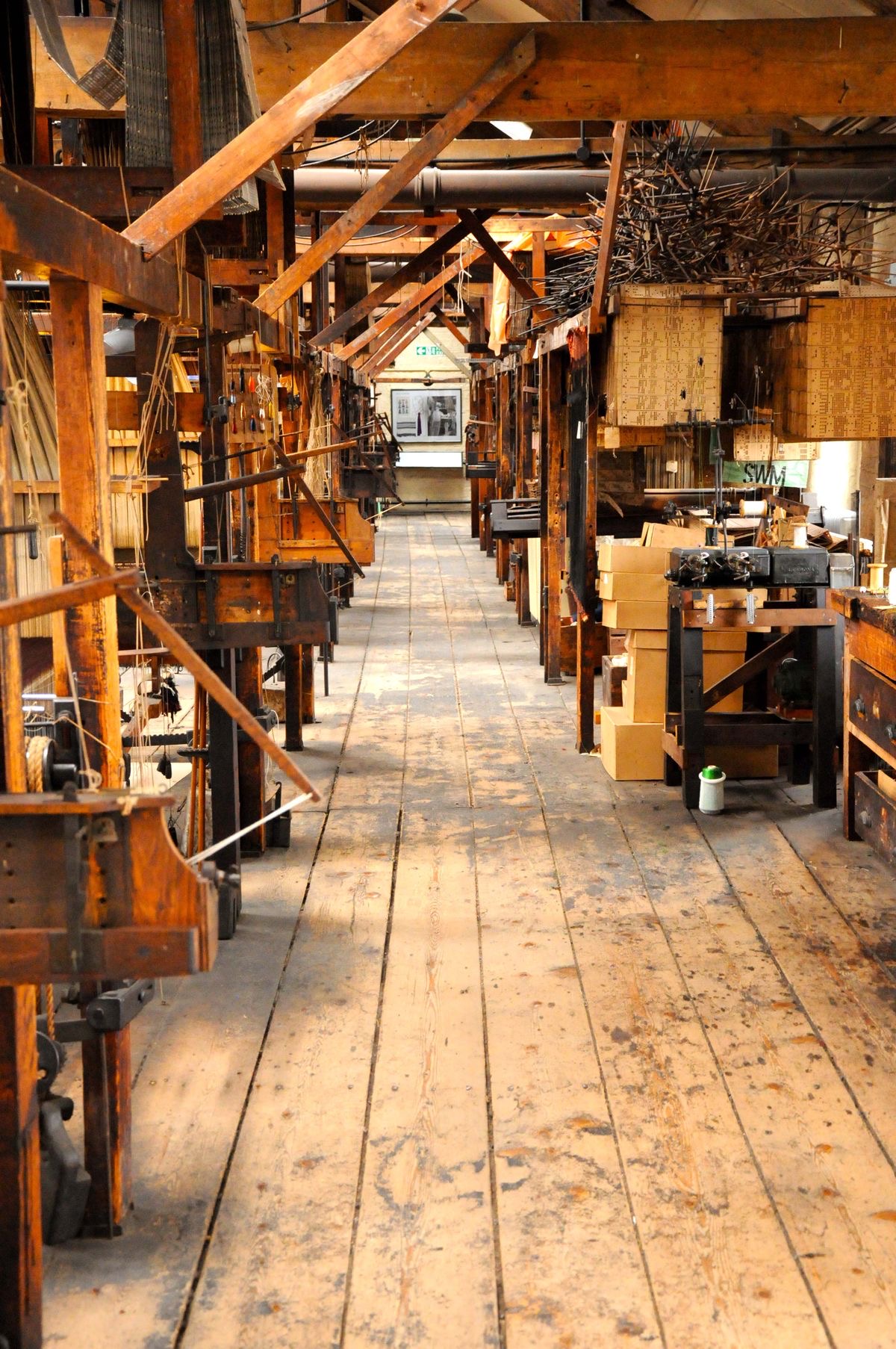 The interior of a Macclesfield silk mill, wooden floors stretching down between weaving frames.