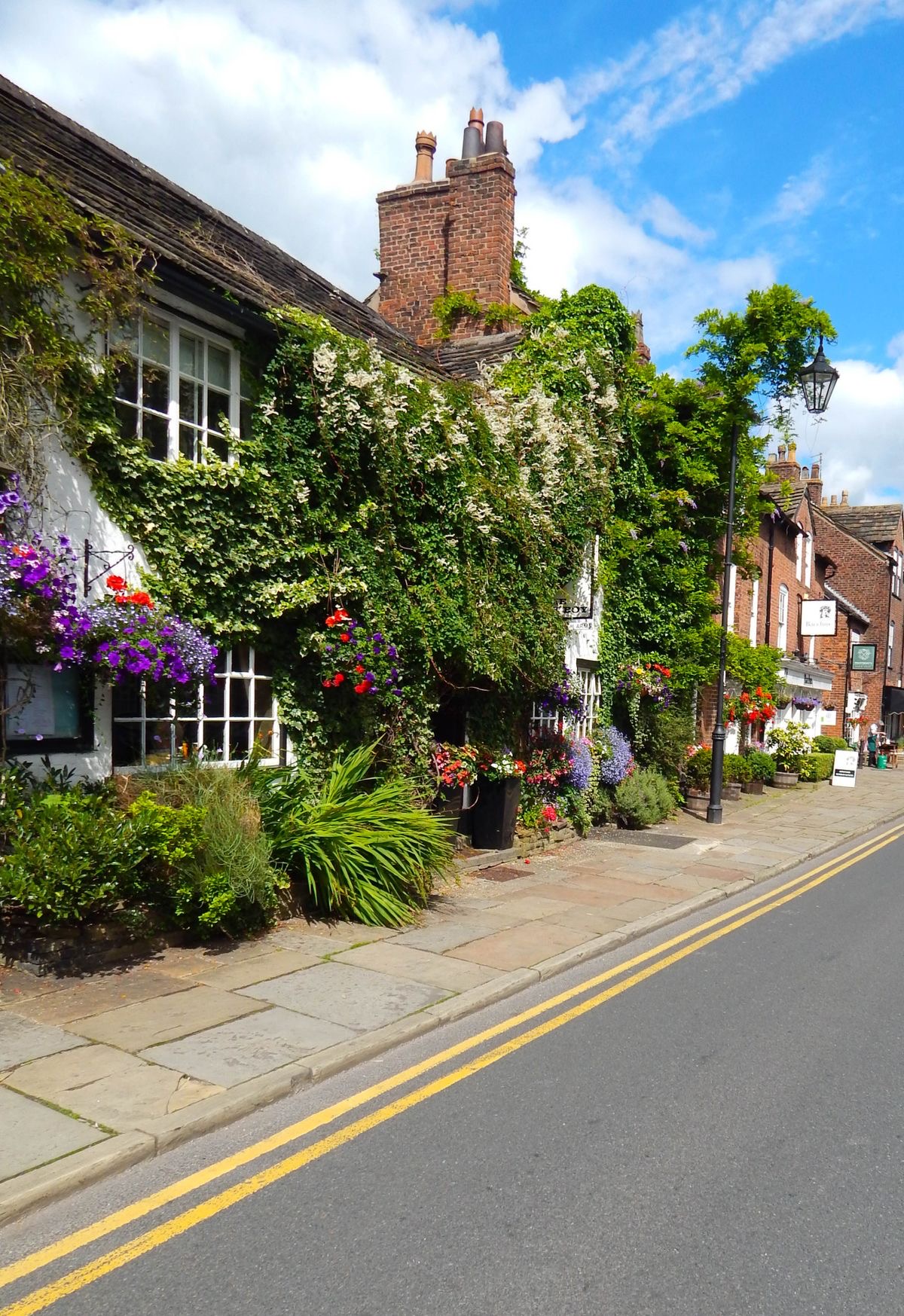 An ivy and flower-covered building on a Prestbury village street.